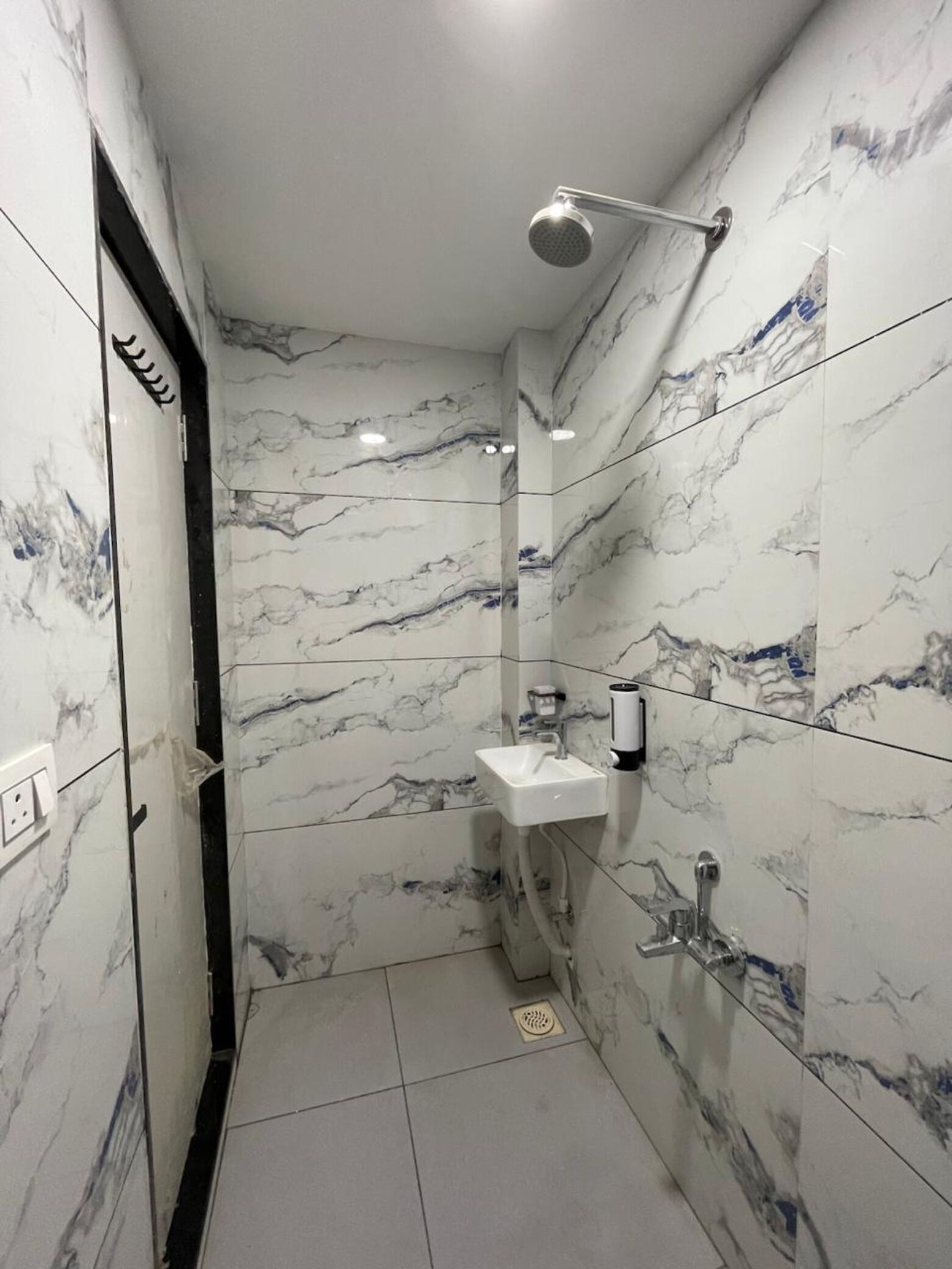 Un baño con paredes de mármol, un lavamanos y una ducha.
