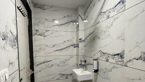 Un baño con paredes de mármol, un lavamanos y una ducha.