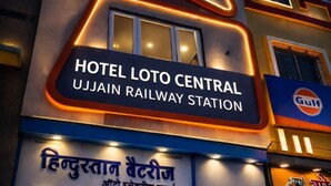 Exterior del Hotel Lotto Central, cerca de la estación de tren de Ujjain, con un cartel que muestra el nombre del hotel y el nombre de la estación, y un escaparate con varias tiendas.