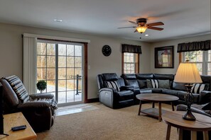 A living room with a sectional sofa, a coffee table, a lamp, and a ceiling fan.