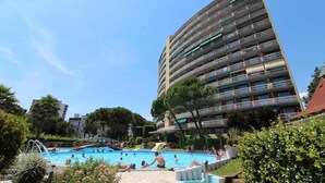 A multi-story building with balconies, a swimming pool, and surrounding greenery. - Holiday apartment mit Pool und Balkon (Lignano Sabbiadoro)