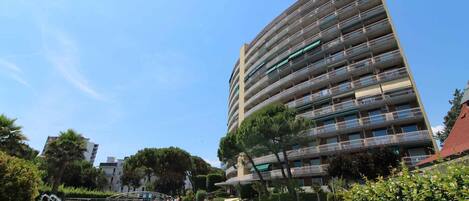 A multi-story building with balconies, a swimming pool, and surrounding greenery.