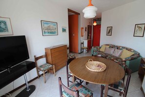 Ein Wohnzimmer mit Fernseher, Holzmöbeln, einem runden Tisch und einem Sofa.