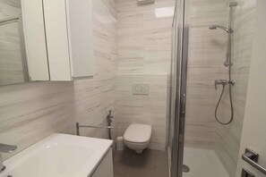 Een moderne badkamer met douche, toilet en wastafel.