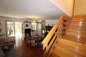 A dining area with a wooden staircase leading to an upper floor. - Holiday apartment with terrace and garden (Lignano Sabbiadoro)