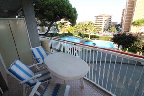 A balcony with a pool, chairs, and a table. - Holiday apartment mit Pool (Lignano Sabbiadoro)