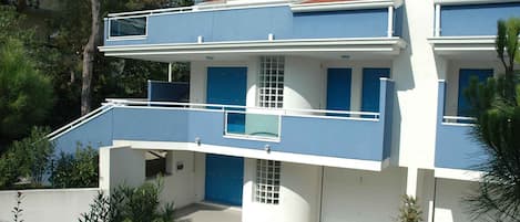 Un edificio moderno de dos pisos con balcones, antena parabólica y garaje.