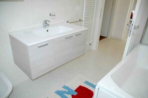Ein Badezimmer mit Waschbecken, Waschtisch und Badewanne.