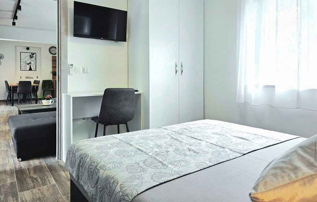 Une chambre à coucher comprenant un lit, un bureau, une chaise, un téléviseur et une armoire.