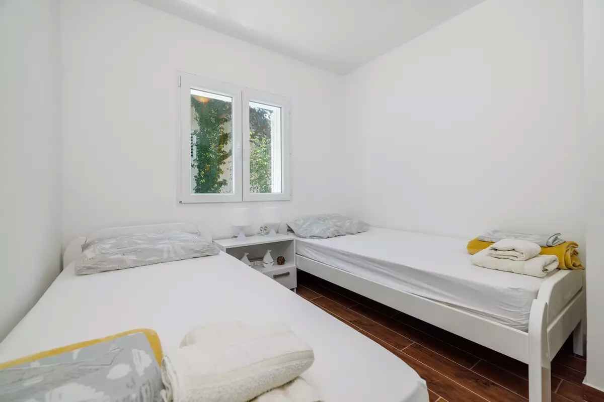 Ein kleines, sauberes Zimmer mit zwei Betten, einem Fenster und Holzboden.