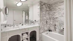 Une salle de bain avec un meuble-lavabo en marbre, un grand miroir, une baignoire et un espace douche.