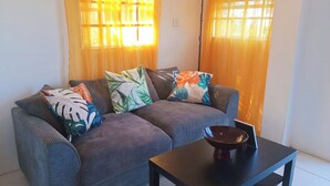A living room with a grey sofa, colorful pillows, a dark coffee table, and a floor lamp.