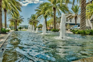 A water fountain with palm trees and a building in the background. - King on main level· Pool + 4 E-bikes & fenced yard (Inlet Beach)