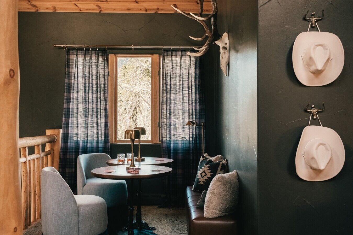 Een gezellige kamer met een ronde tafel, twee stoelen, een bank en een raam met gordijnen.