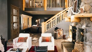 Ein geräumiger Wohnbereich mit hoher Decke, einer Treppe und einer Steinwand.