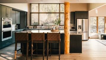 A modern kitchen with a large island, dark cabinets, and a wooden column.