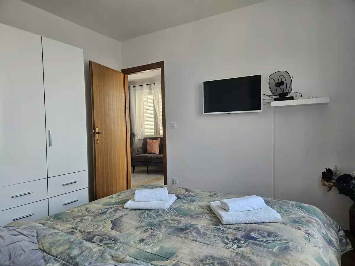 A bedroom with a bed, a TV, a fan, and a wardrobe.