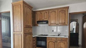 Une cuisine avec des meubles de rangement en bois, une cuisinière et un évier.