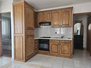 Une cuisine avec des meubles de rangement en bois, une cuisinière et un évier.