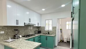 Una cocina moderna con armarios blancos, encimera de granito y una isla central.