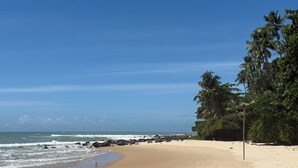 A beach with clear skies, calm waves, and a rocky shoreline. - Luxury Nature Retreat: Hummingbird House (Tibau do Sul)