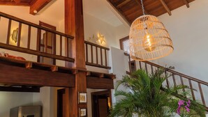 A wooden staircase with a hanging light fixture and a plant with purple flowers. - Luxury Nature Retreat: Hummingbird House (Tibau do Sul)