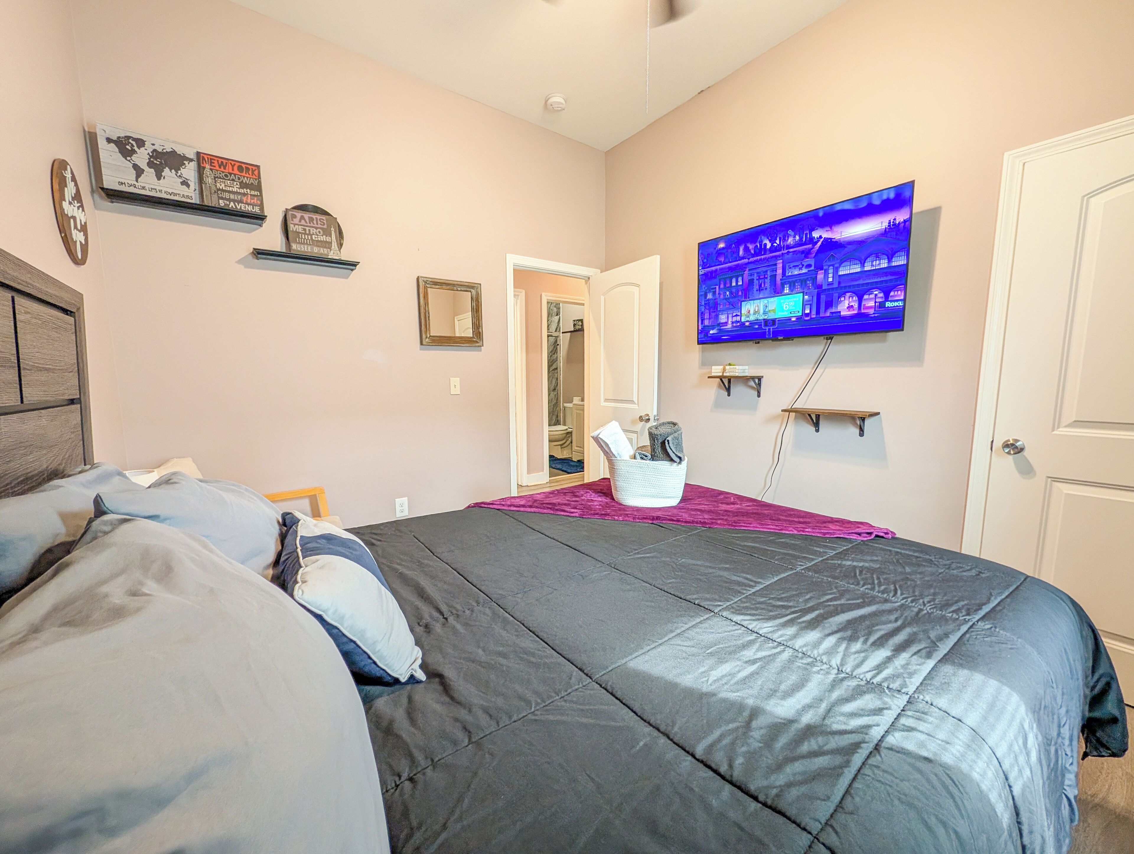 A bedroom with a bed, a television, a mirror, and a door.