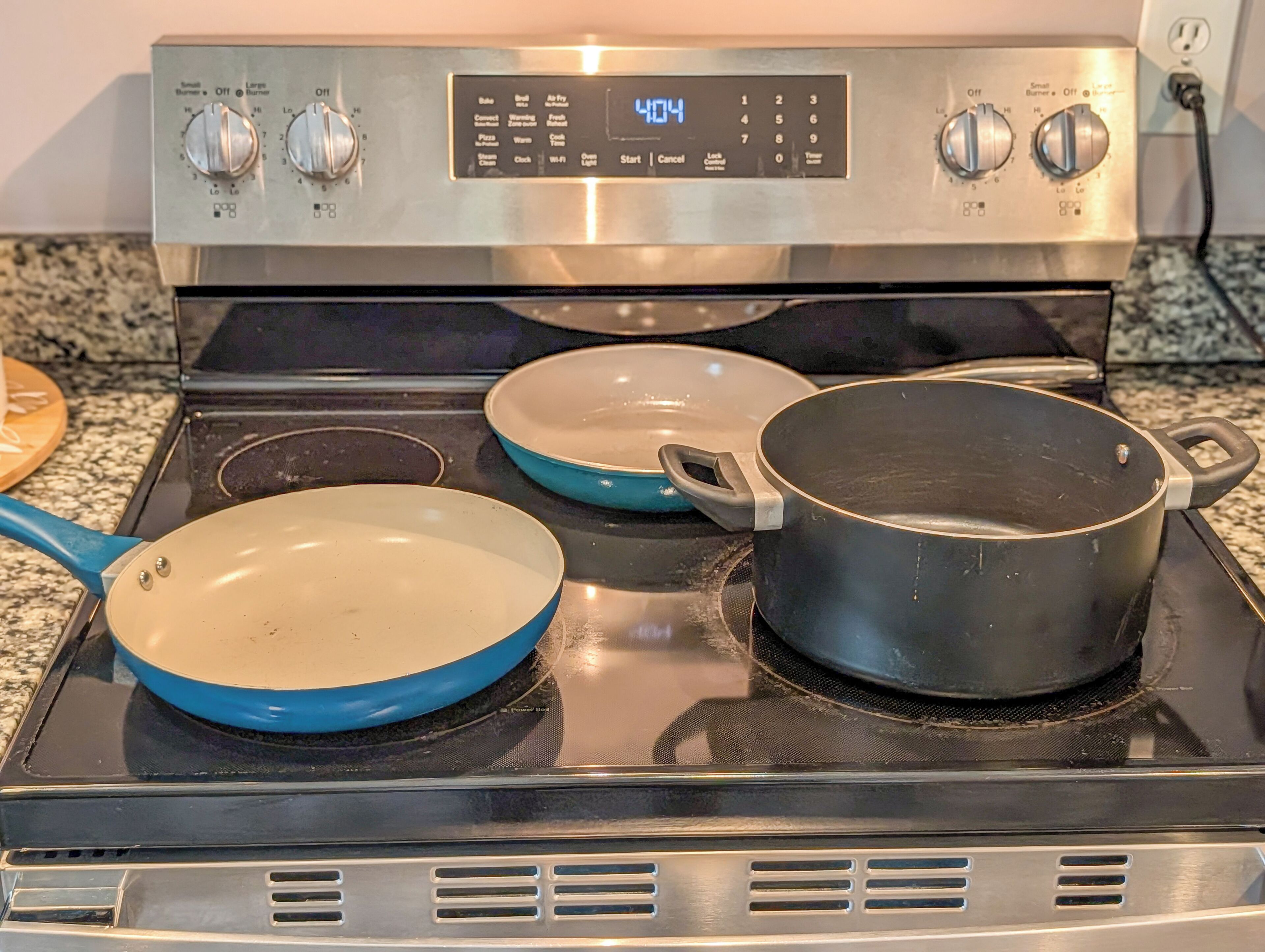 Een keuken met een fornuis, twee koekenpannen en een pan.