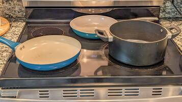 Een keuken met een fornuis, twee koekenpannen en een pan.