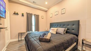 Um quarto com uma cama grande, um ventilador de teto, uma TV e uma janela com cortinas.