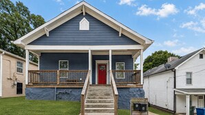 Uma casa de dois andares com porta vermelha, varanda frontal e caixa de correio com o número 1002.