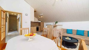 A modern living room with a round dining table, a sofa, and a kitchen area in the background. - Holiday flat with terrace and sea view (Novi Vinodolski)