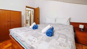 A bedroom with a bed, two rolled towels, a wooden wardrobe, and a nightstand. - Holiday flat with terrace and sea view (Novi Vinodolski)