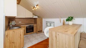 A compact kitchen with wooden cabinets, a built-in oven, and a small island. - Holiday flat with terrace and sea view (Novi Vinodolski)