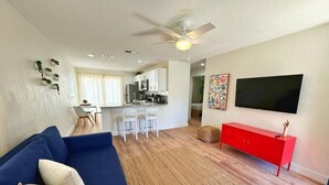 A living room with a blue sofa, a red cabinet, and a television on the wall. - NEW Gorgeous Sunshine-Up 6 Guests-Private Backyard (Port Orange)