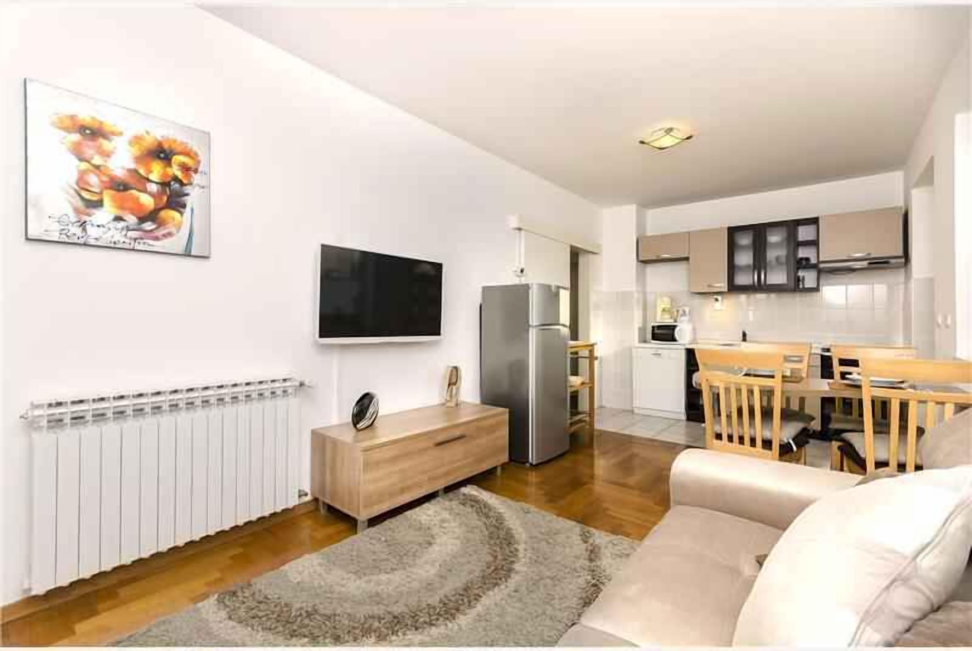 Un salon moderne doté d’un téléviseur à écran plat, d’un meuble en bois et d’un coin repas avec une table et des chaises en bois.