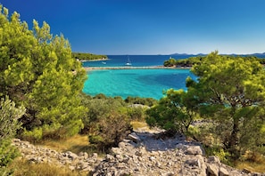 A coastal landscape with clear turquoise waters, rocky terrain, and dense green pine trees. - Holiday Apartment Milenko Ivic 3 (4+0) (Vodice)