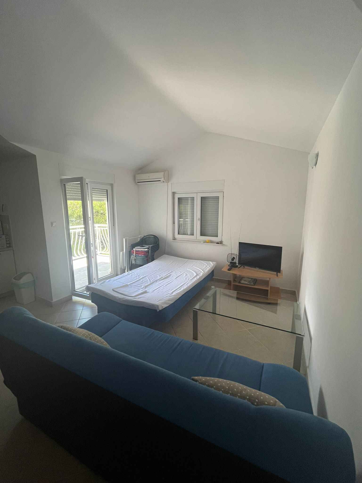 Quarto com cama, televisão, janela e varanda.