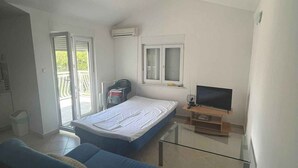 Une chambre avec un lit, une télévision, une fenêtre et un balcon.