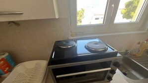 Une cuisine équipée d’une cuisini ère, d’un évier et d’une fenêtre.