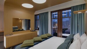 A modern hotel room with a large bed, a wooden headboard, a mirror, and a view of the city at night. - Charming 3BR Home in Union (Union)