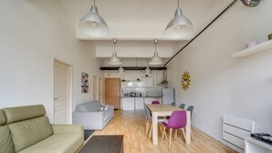 A compact living space with a sofa, dining table, and chairs, a kitchenette, and a small dining area.