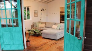 A living room with a light-colored sofa, a potted plant, and a teal door.