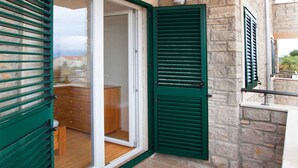 A room with a sliding glass door, a wooden cabinet, and a stone wall. - Holiday Apartment Trio 12 (2+0) (Srima)