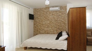 Un dormitorio con cama, un armario de madera, un televisor y una pared con diseño de ladrillo.