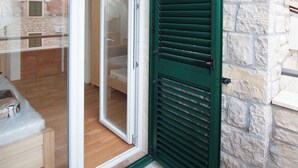 A room with a sliding glass door leading to an outdoor area, stone walls, and a wooden floor. - Holiday Apartment Trio 13 (2+1) (Srima)