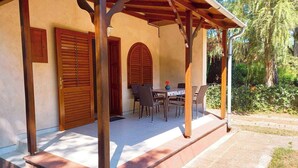 Una veranda coperta con tavolo e sedie, porte in legno e una struttura a pergola.