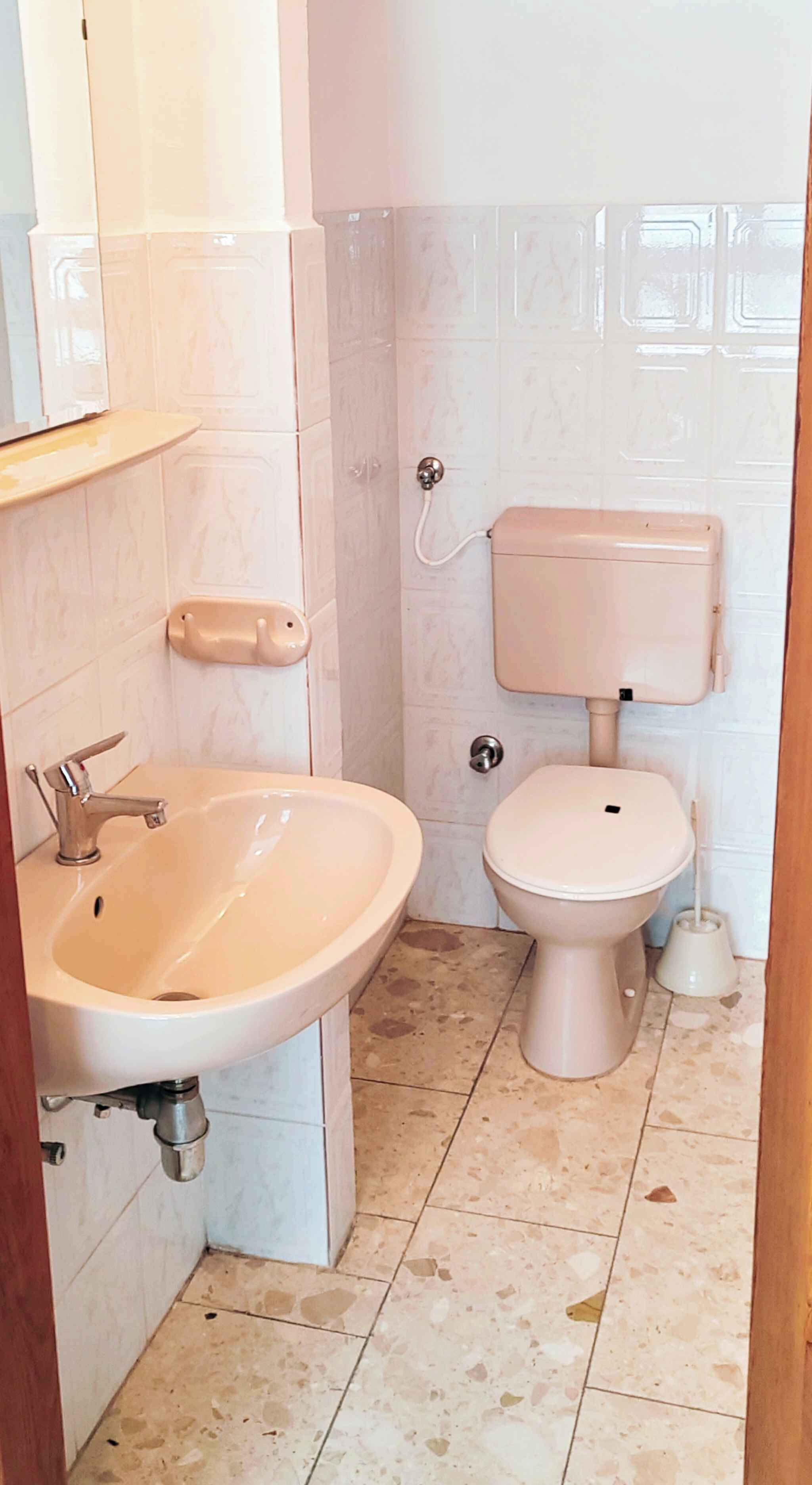 A small bathroom with a sink, toilet, and a toilet paper holder.