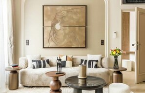 A modern living room with a beige sofa, two side tables, and a large abstract painting on the wall. - A REFINED TOUCH OF ELEGANCE WITHIN WALKING DISTANCE OF MARAIS, POMPIDOU & LOUVRE (Paris)