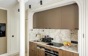 A modern kitchen with wooden cabinets, a marble backsplash, and a built-in dishwasher. - A REFINED TOUCH OF ELEGANCE WITHIN WALKING DISTANCE OF MARAIS, POMPIDOU & LOUVRE (Paris)